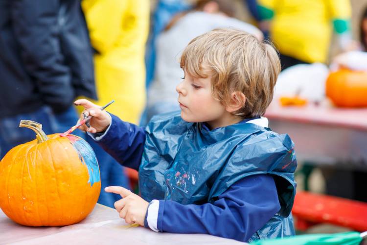 kid painting a pumpkin 