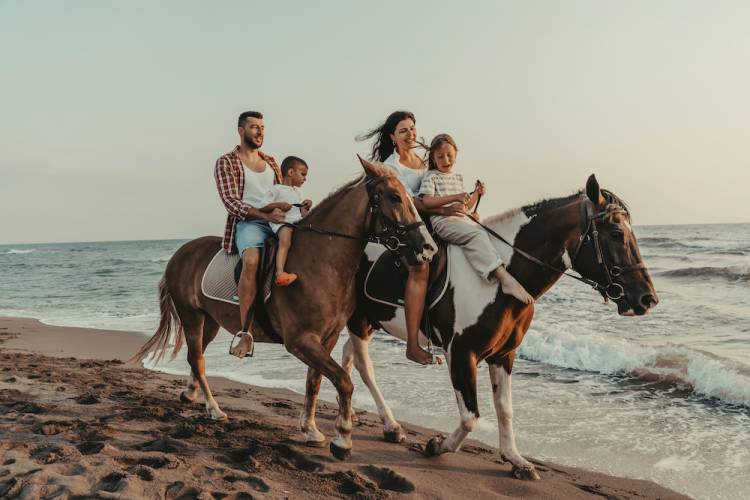 family riding horses on beach