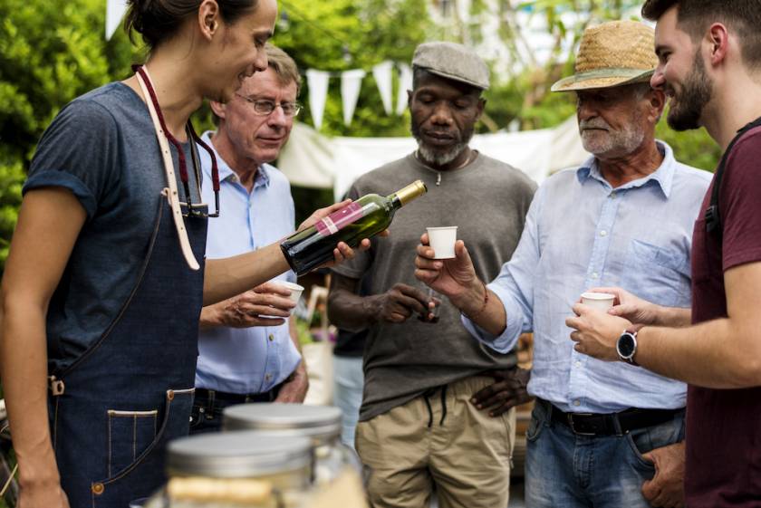 person pouring wine samples for a group